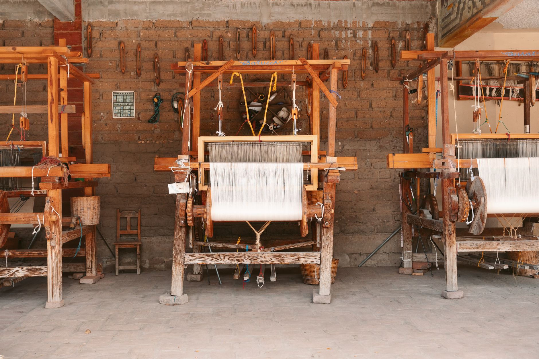 Three wooden looms in an artisan workshop in Oaxaca, Mexico, showcasing local craftsmanship.